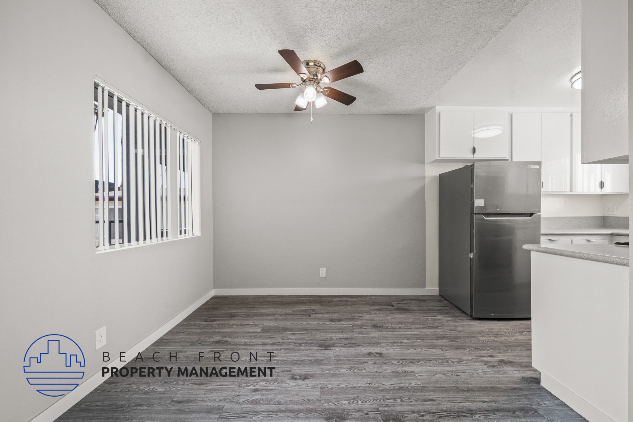 A spacious kitchen and living room with a ceiling fan and wooden flooring.